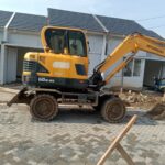 Mini wheel excavator bekerja di proyek jalan lingkungan perkotaan